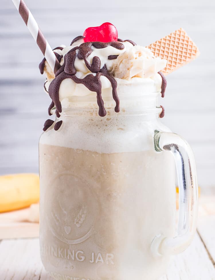 Banana Milkshake in a mason jar topped with chocolate syrup, maraschino cherry and wafer