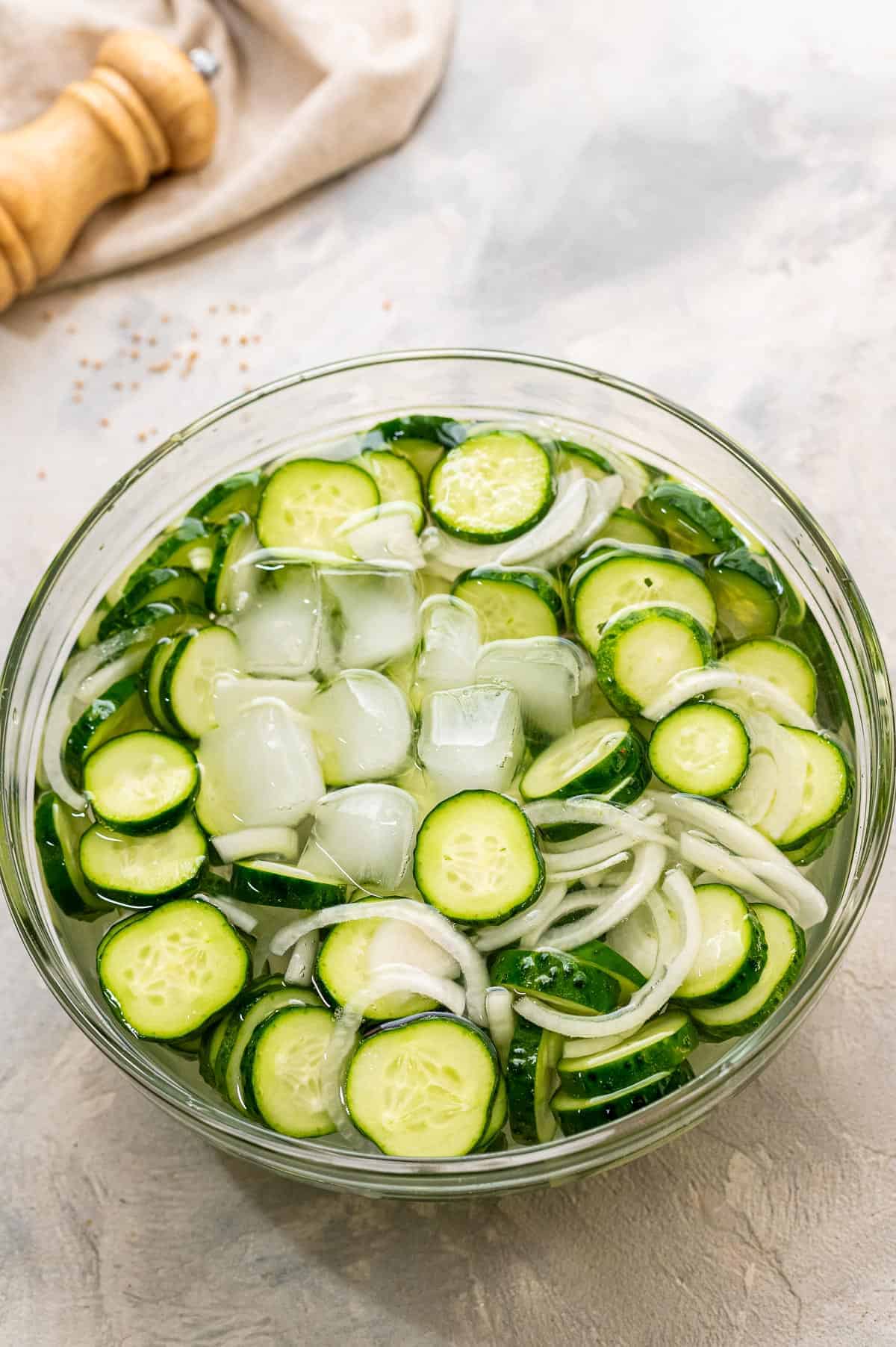 Glass bowl with cucumbers, ice and onions
