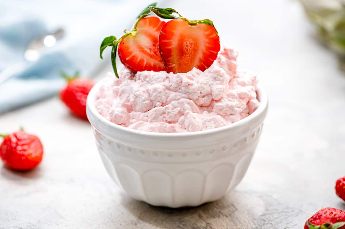 A white bowl with Cottage Cheese Jello Salad garnished with fresh strawberries