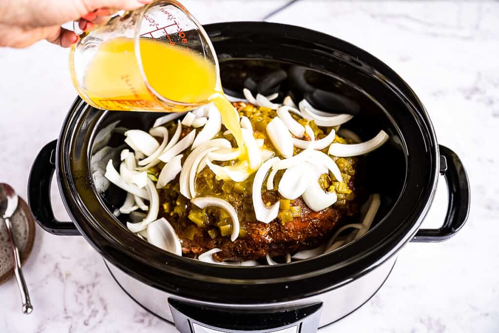 Pouring citrus juices into crock pot for carnitas