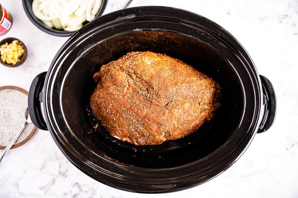 Seasoned pork shoulder in crock pot before cooking
