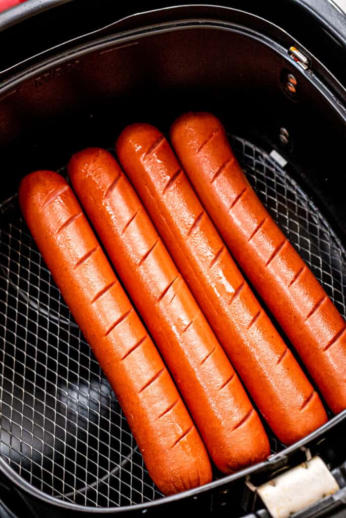 Cooked hot dogs in black air fryer basket