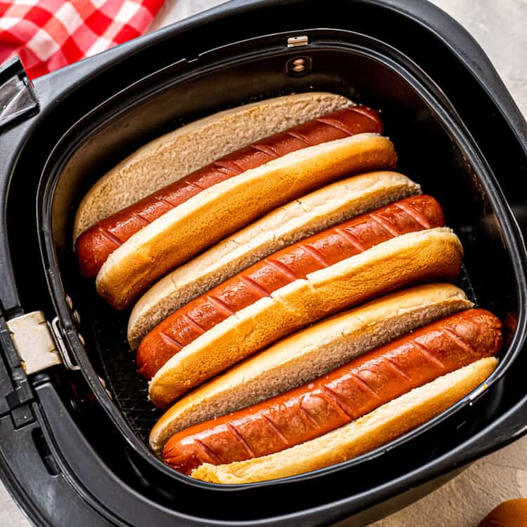 Overhead image of hot dogs in buns in an air fryer basket