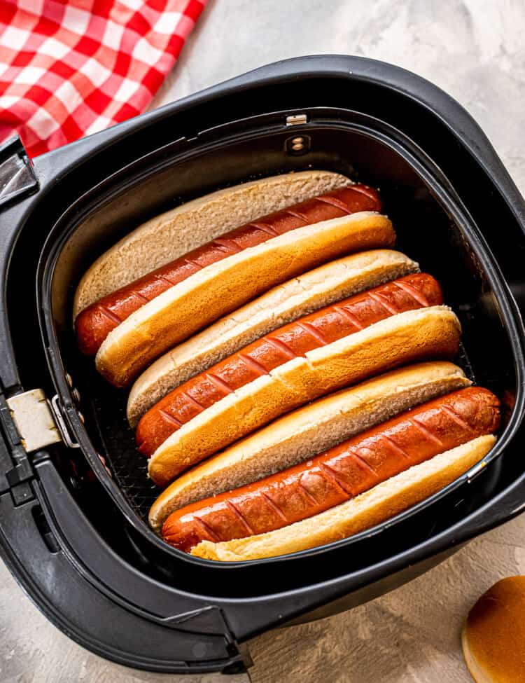 Overhead image of hot dogs in buns in an air fryer basket