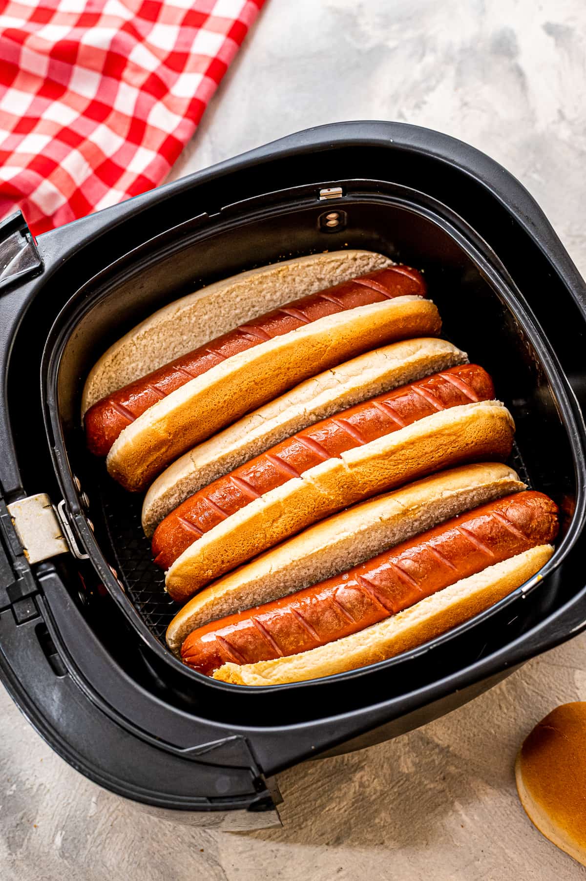 Overhead image of hot dogs in buns in an air fryer basket