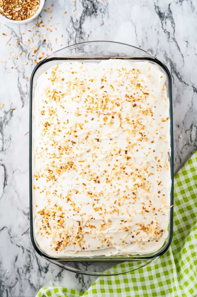 Glass baking dish with frosted cake topped with toasted coconut