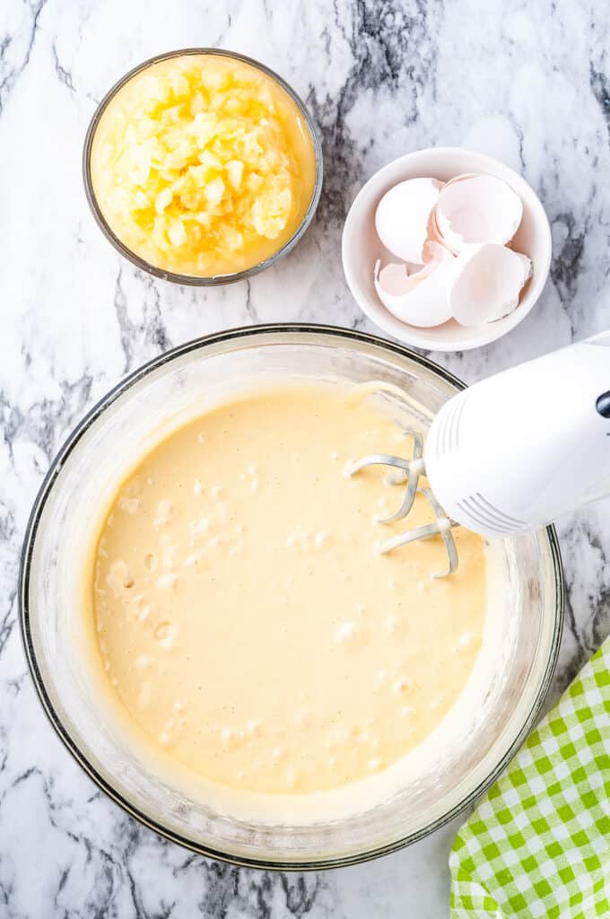 Hand mixer beating cake mix in glass bowl