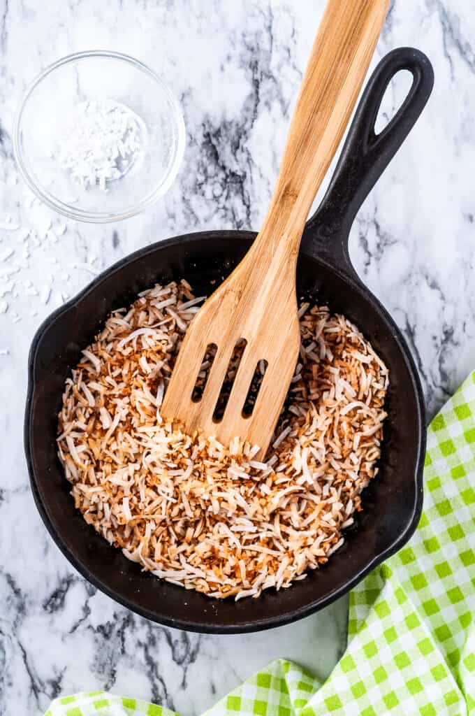 Cast iron skillet with toasted coconut and wooden spatula