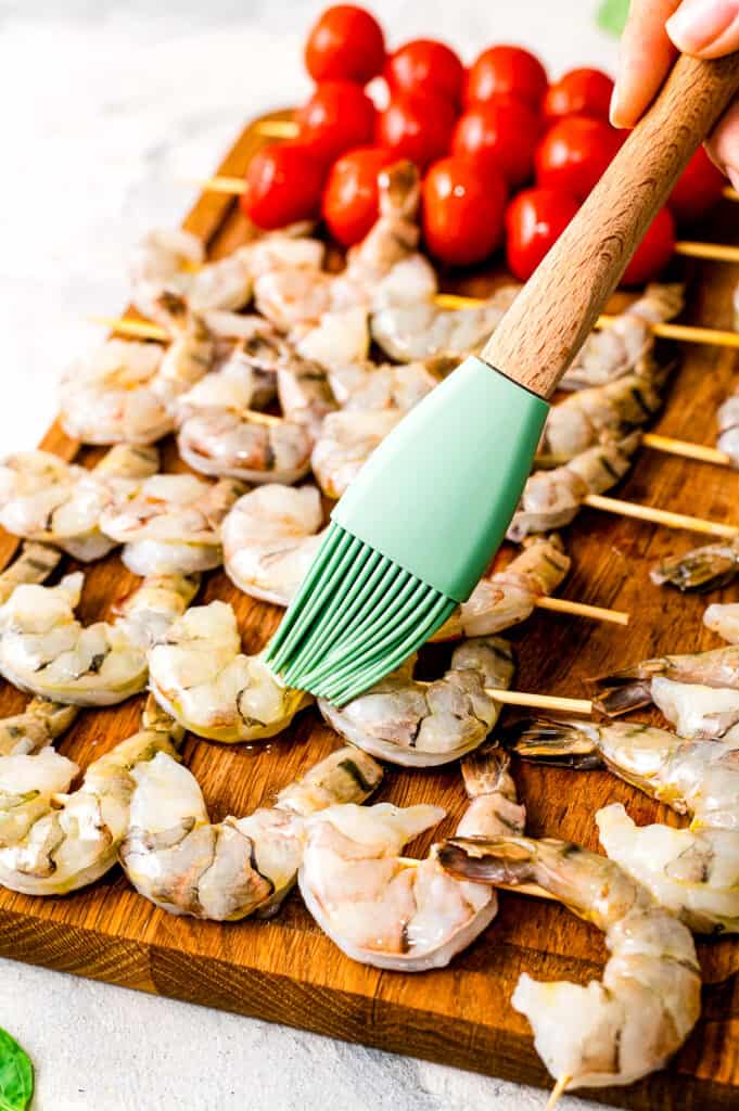 Basting brush putting olive oil in shrimp skewer