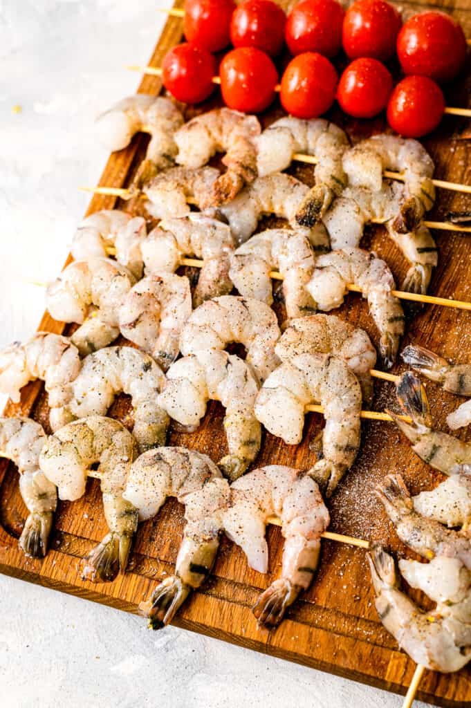 Skewers of shrimp and cherry tomatoes and wooden cutting board