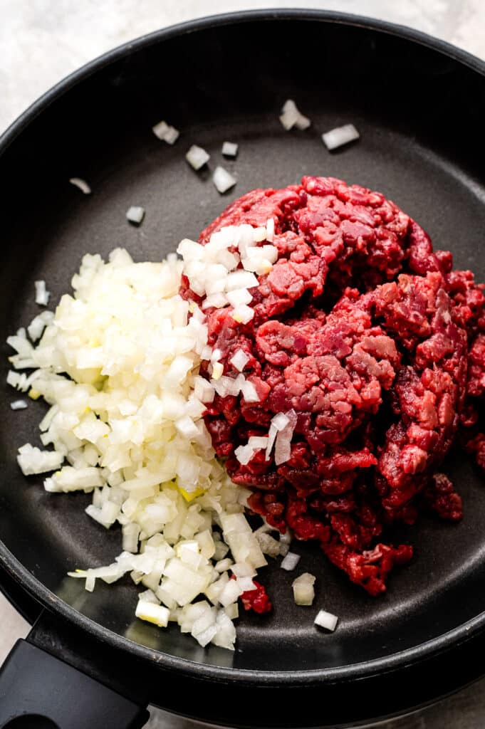 Skillet with onions and ground beef before cooking