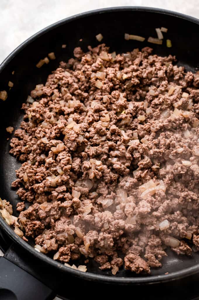 Skillet with cooked ground beef and onions