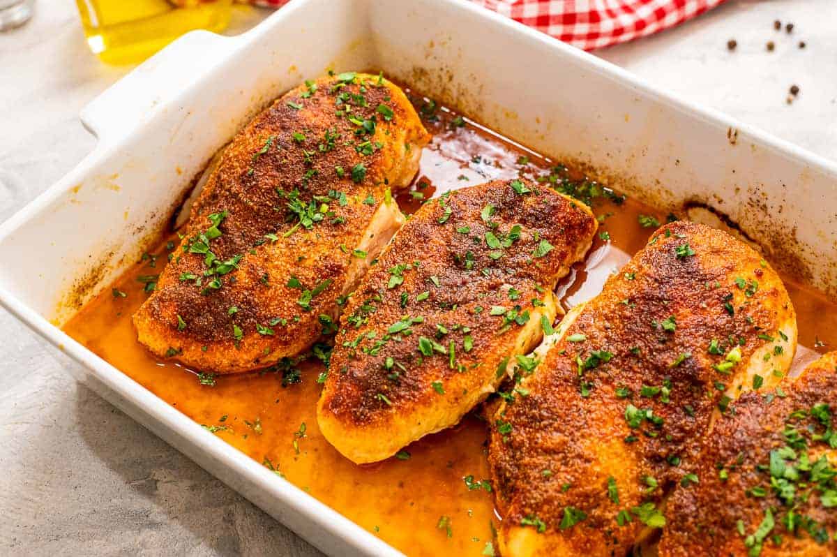 White baking dish with seasoned and baked chicken breasts