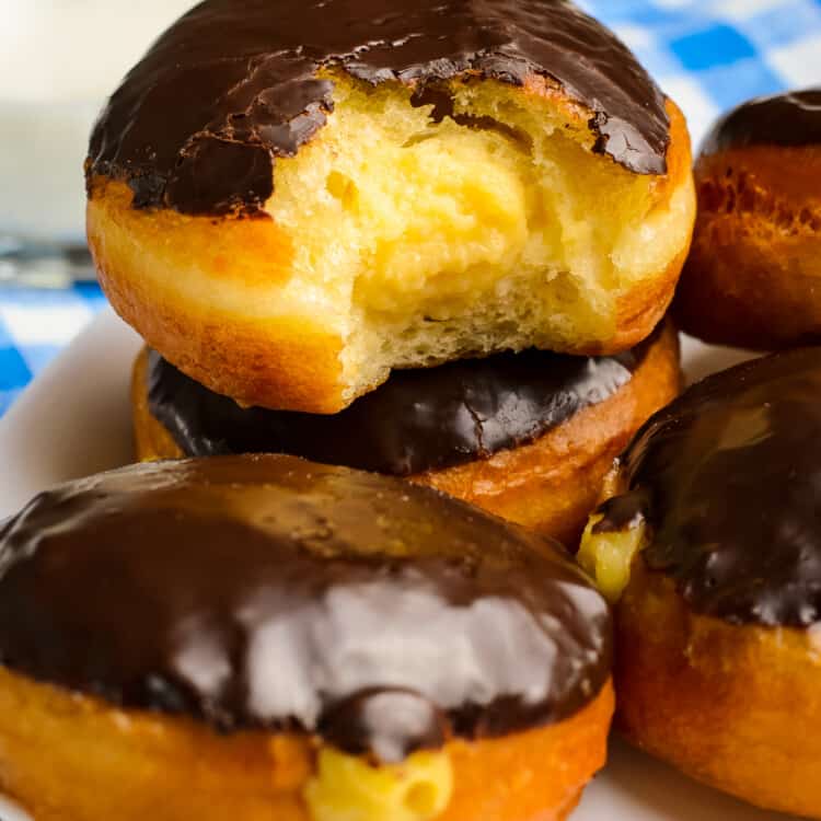 Stack of Boston Cream Donuts with a bite out of the middle