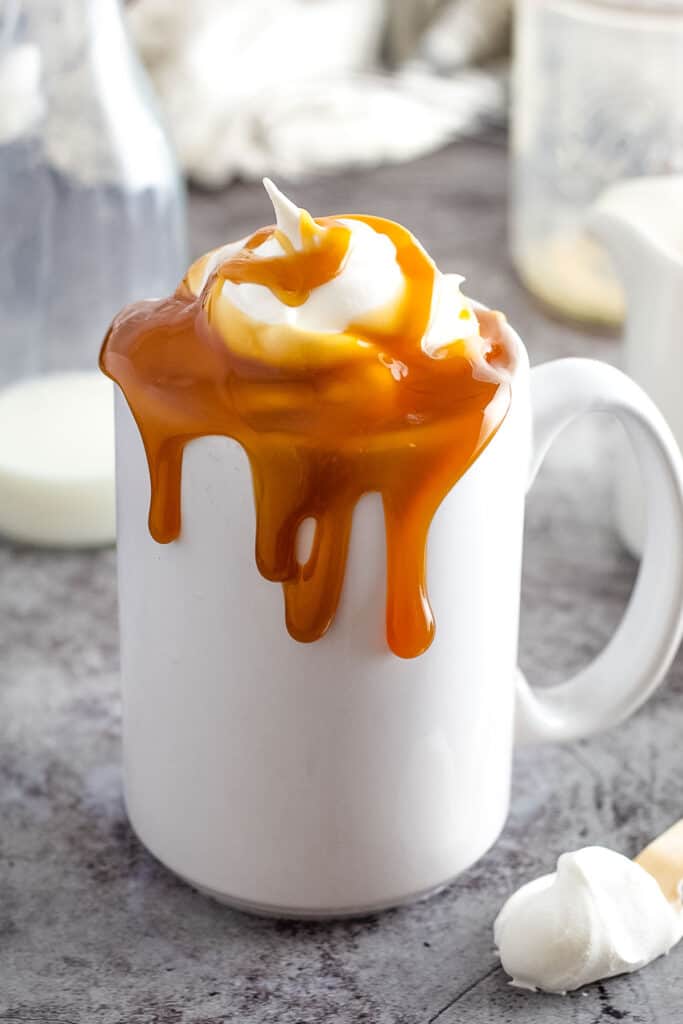 White coffee mug with whipped cream and caramel on top
