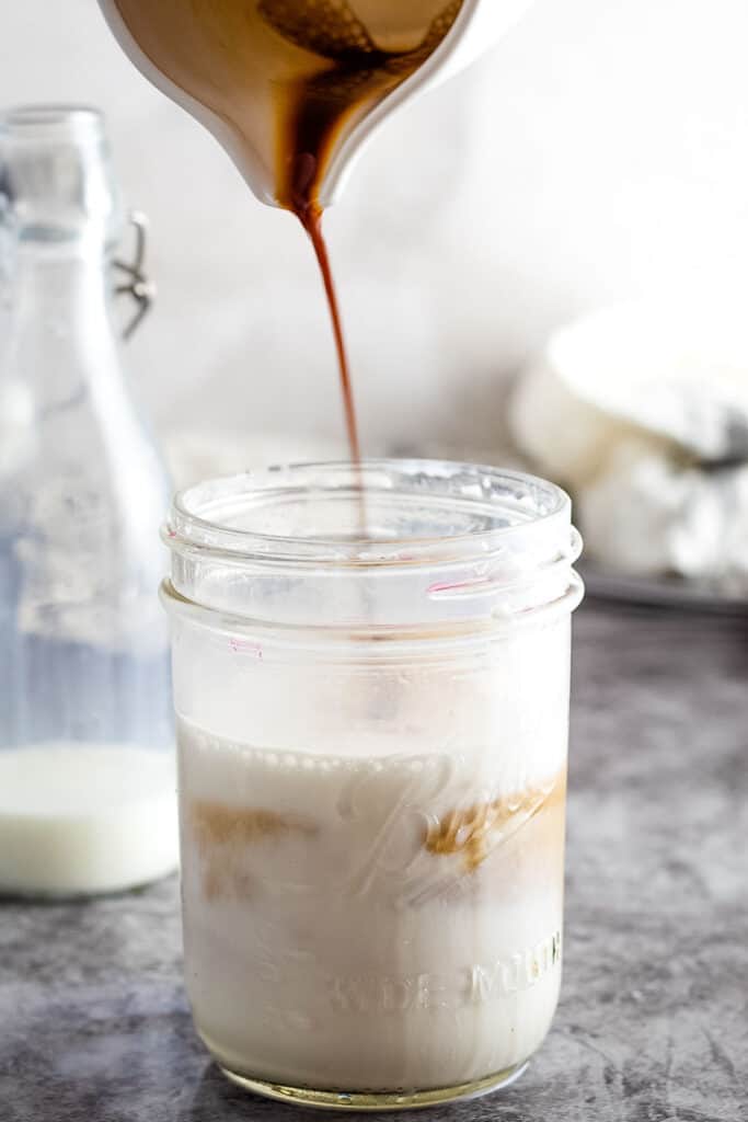 Pouring vanilla syrup into milk into a mason jar
