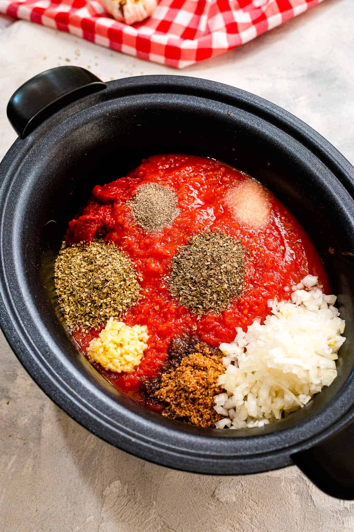 Black crock pot liner with ingredients to make spaghetti sauce