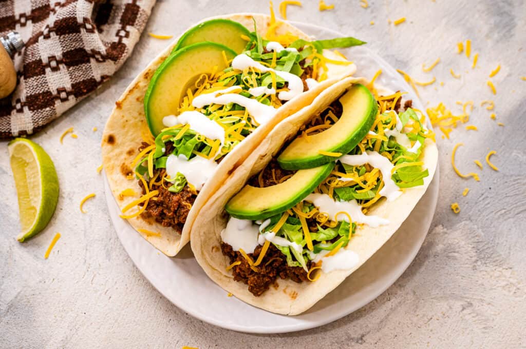 Two softshells with taco meat and toppings on white plate