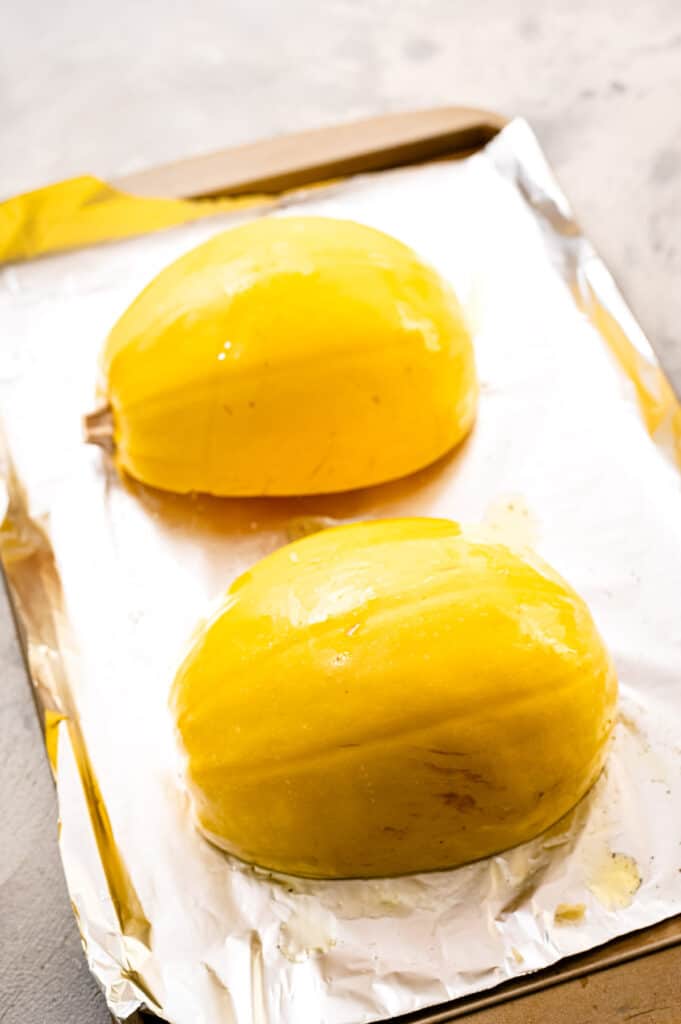 Two halves of spaghetti squash face down on sheet pan