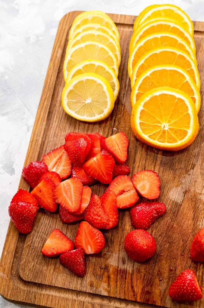 Wood cutting board with sliced lemons, oranges and strawberries