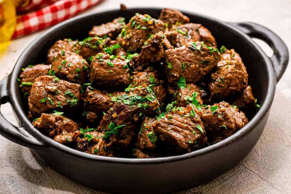 Black bowl with handles with steak bites in it