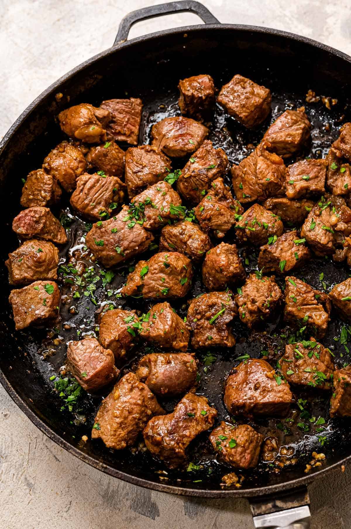 Cast iron pan with pieces of steak in it