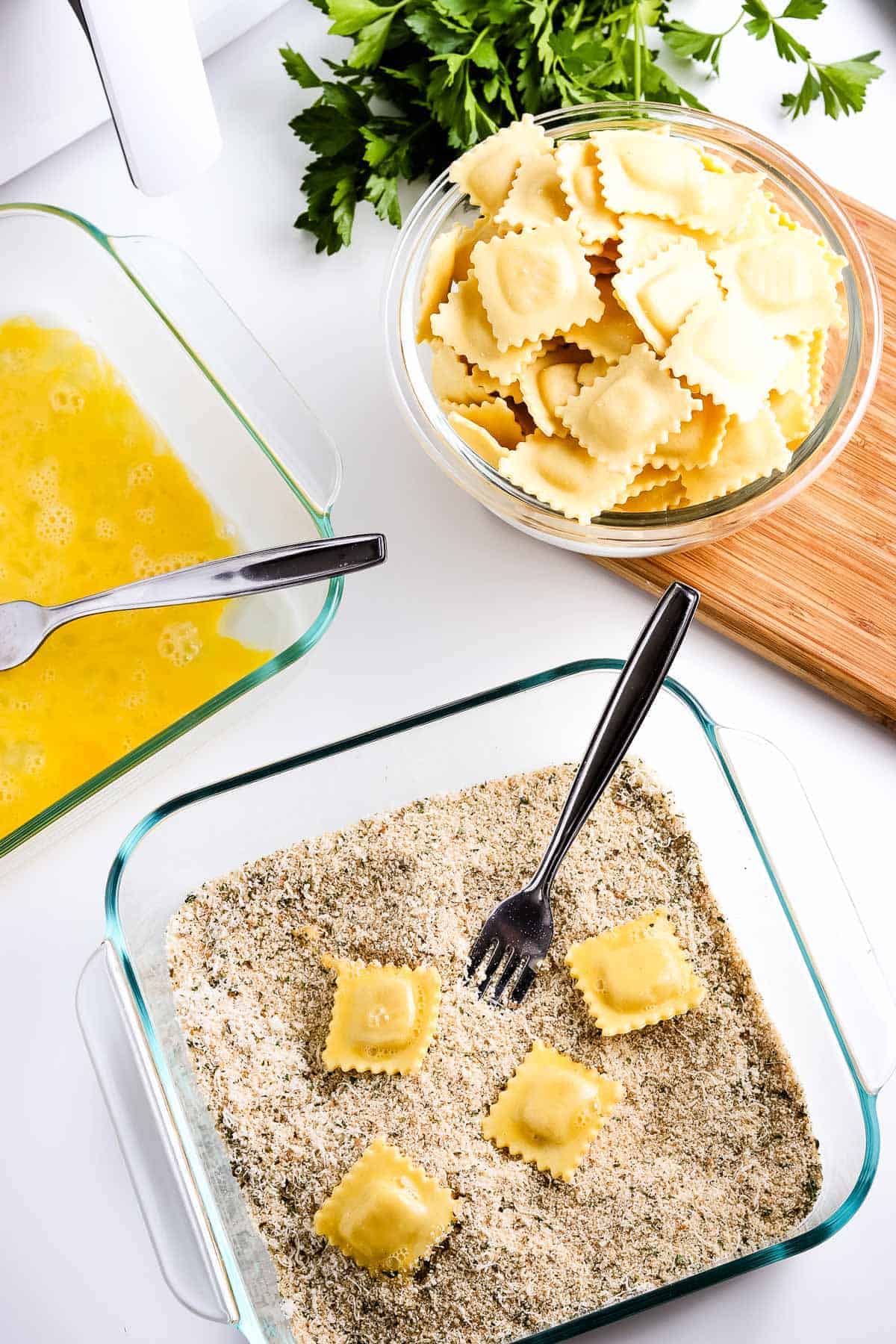 Ravioli being breaded in seasoned breadcrumbs