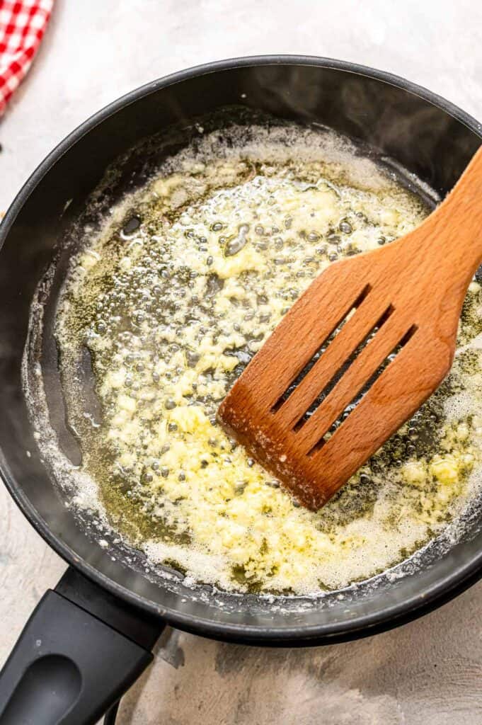 Spatula sautéing garlic in butter