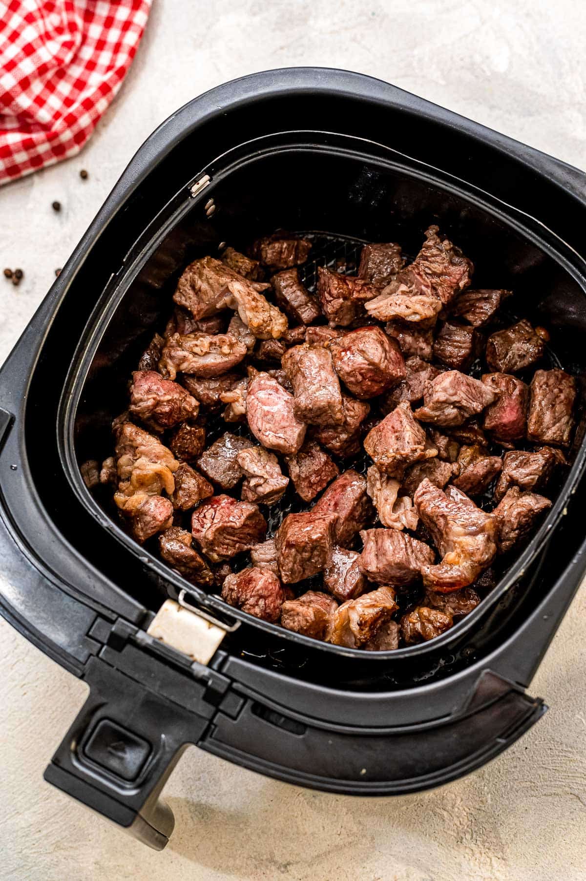 Air Fryer basket with cooked steak pieces
