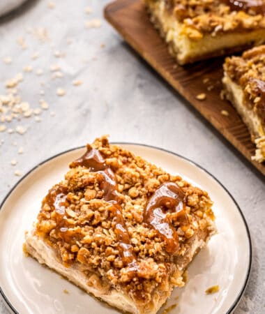 Plate with a apple cheesecake bar on it topped with caramel topping