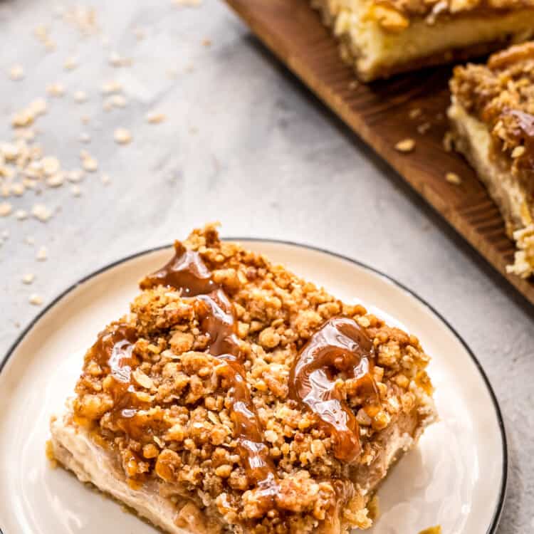 Plate with a apple cheesecake bar on it topped with caramel topping