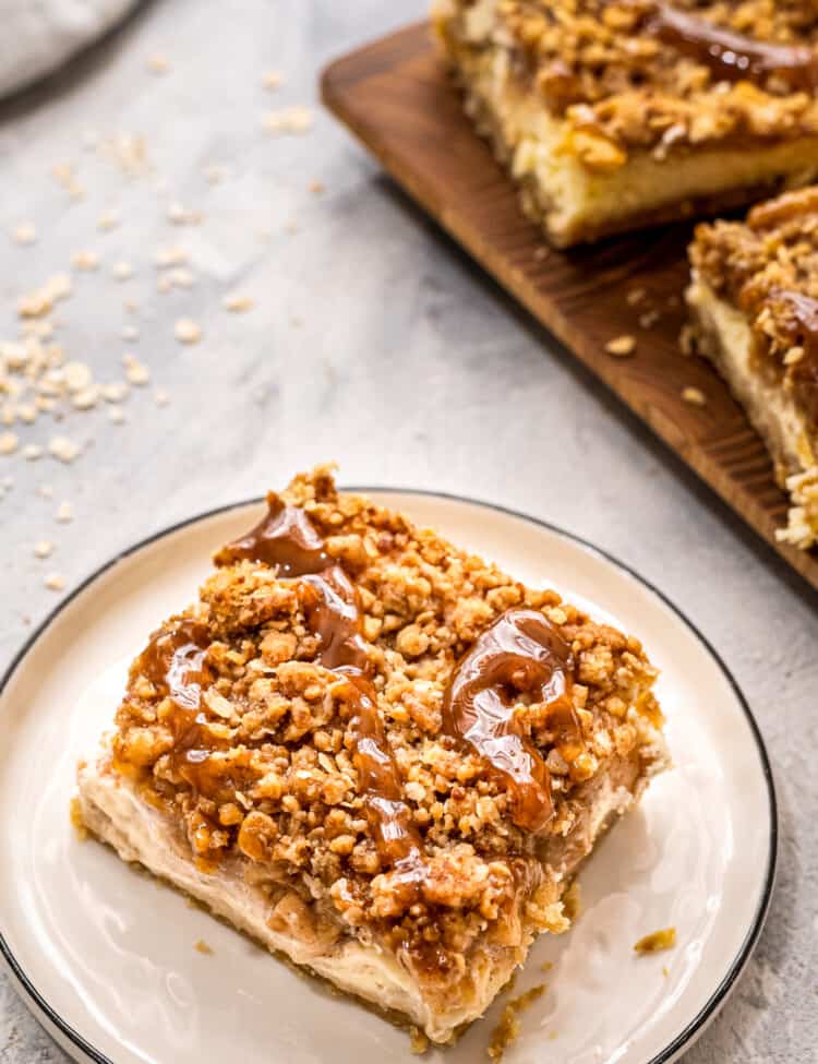 Plate with a apple cheesecake bar on it topped with caramel topping