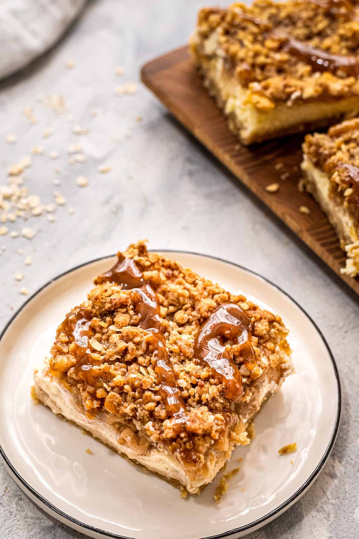 Plate with a apple cheesecake bar on it topped with caramel topping