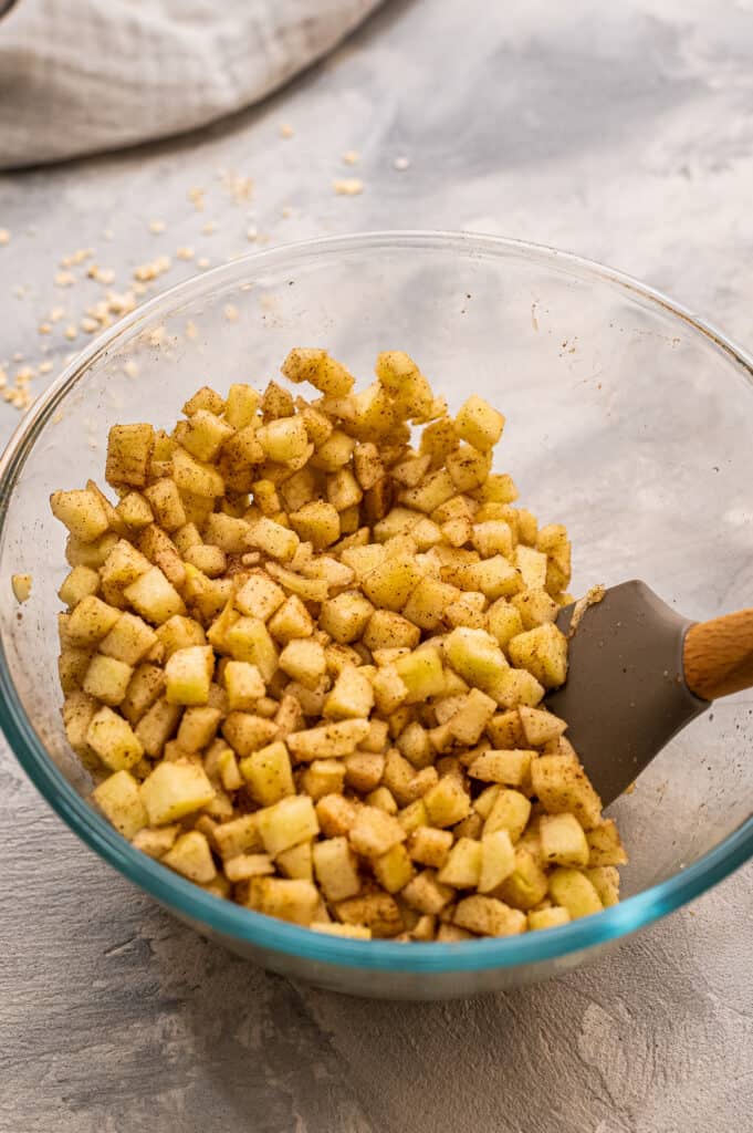 Glass bowl with diced apples tossed in cinnamon