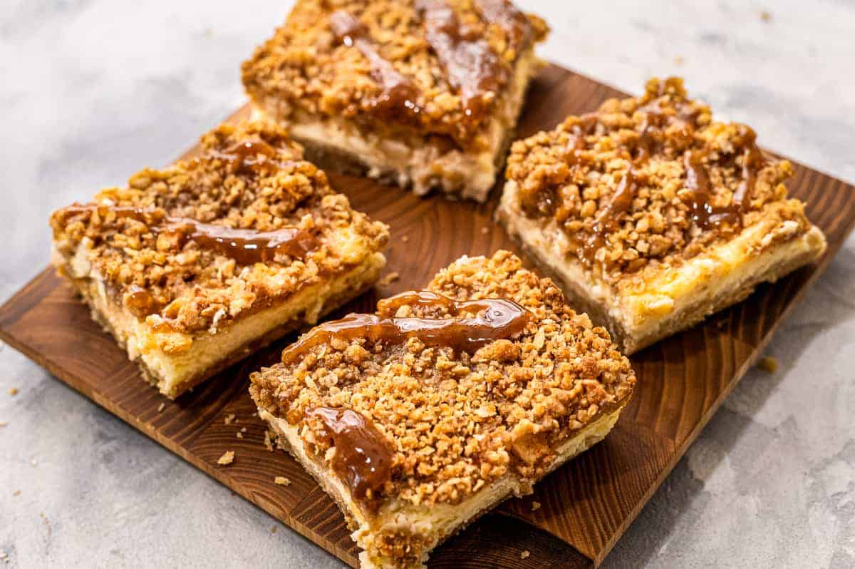 Square cutting board with apple cheesecake bars on it