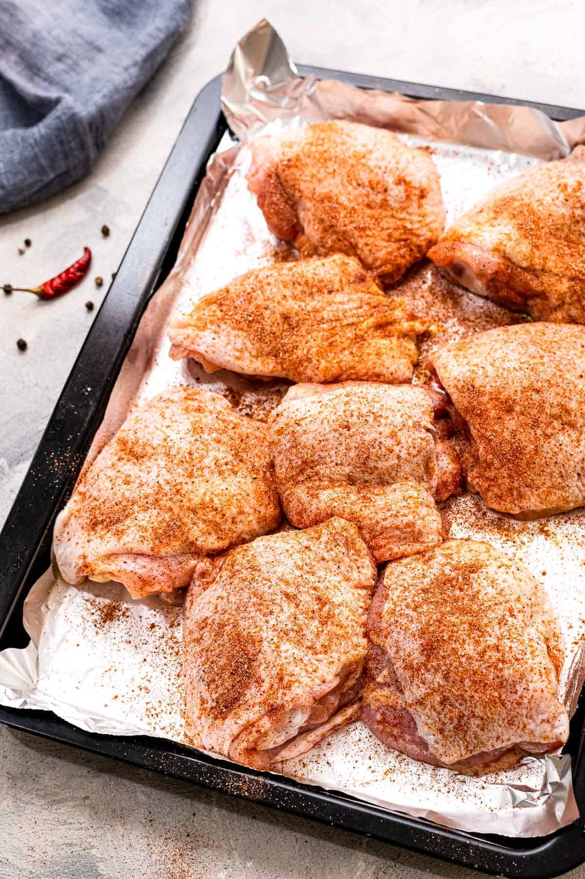 Sheet pan with seasoned raw chicken thighs on it