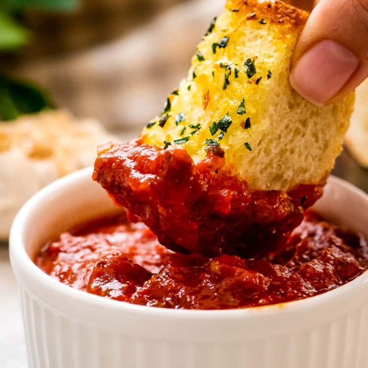 Dipping a piece of garlic bread in marinara