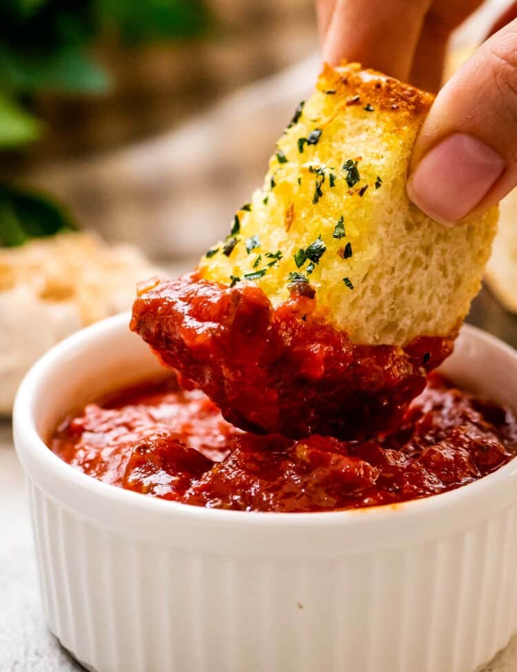 Dipping a piece of garlic bread in marinara