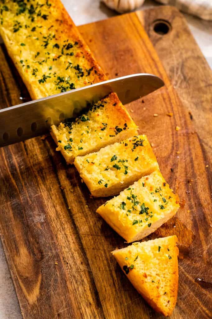 Sliced baked garlic bread with knife