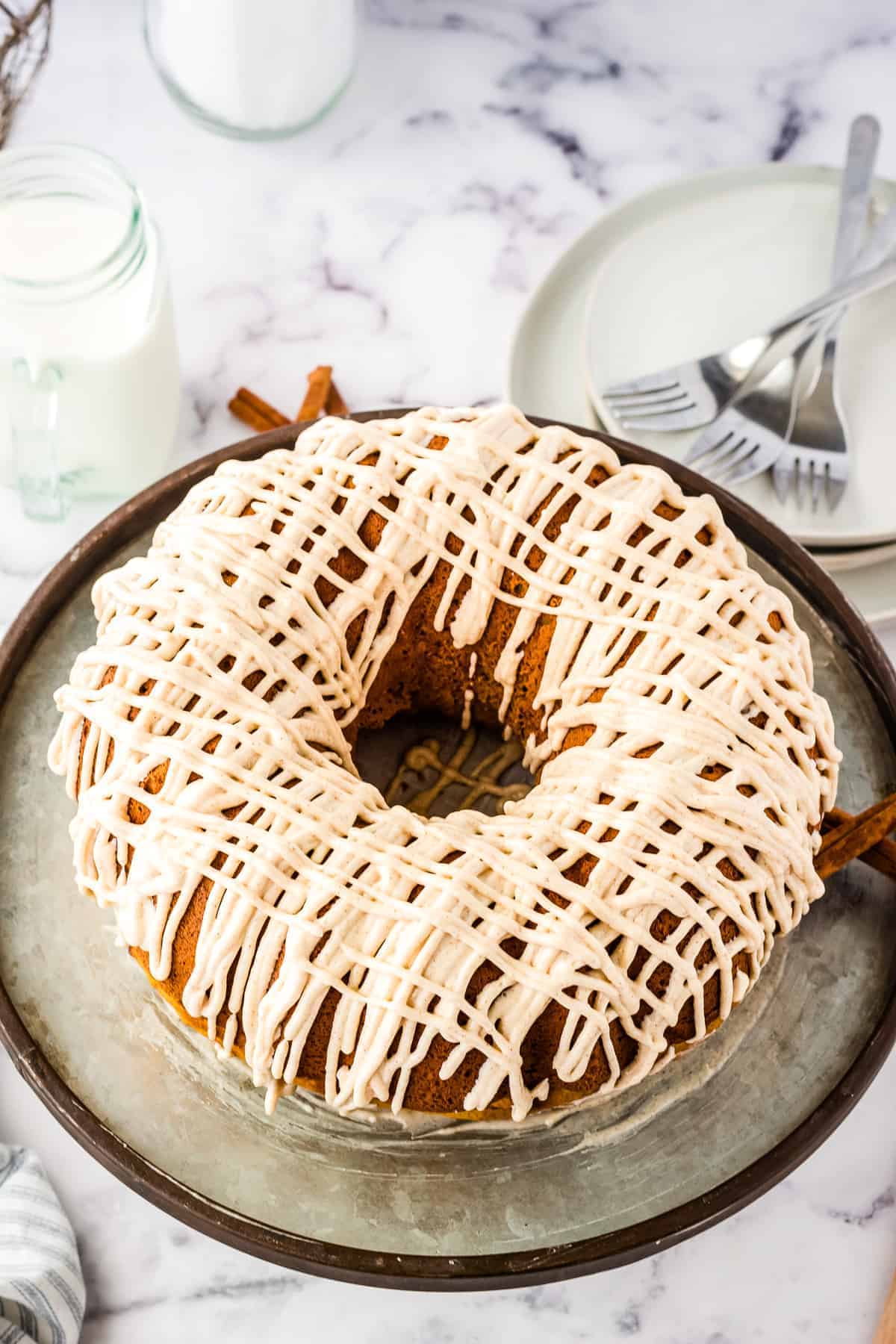 Pumpkin Bundt Cake with a drizzle of cream cheese frosting on cake stand