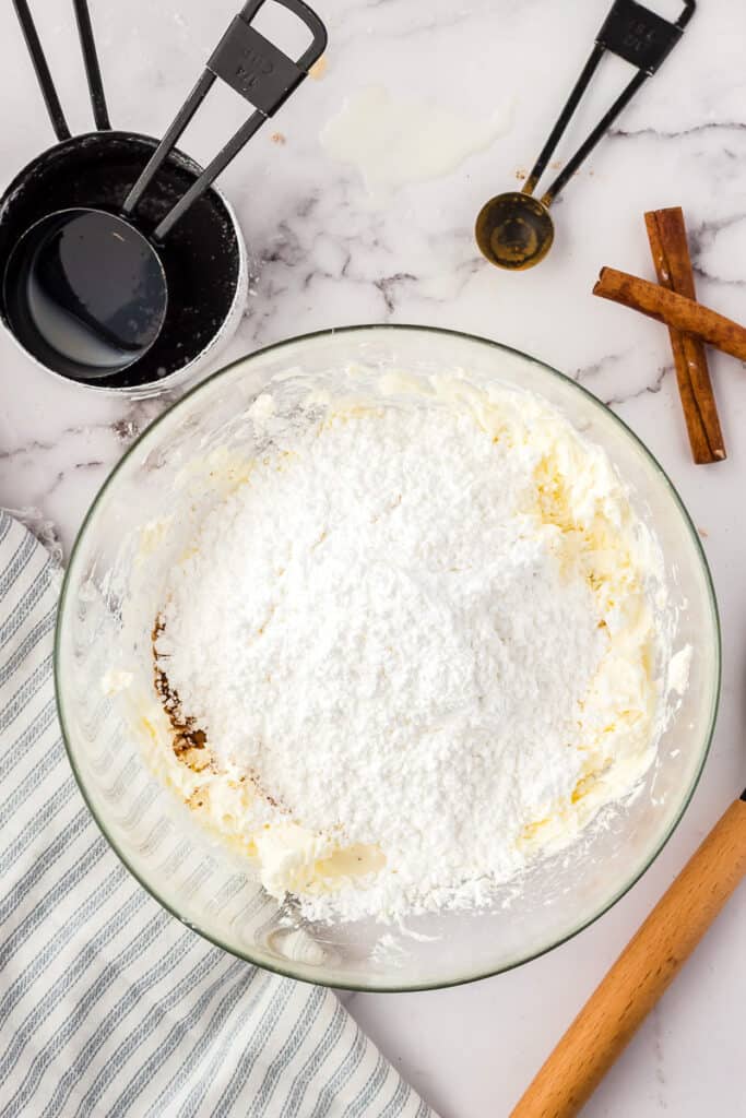Glass mixing bowl with cinnamon cream cheese frosting before mixing
