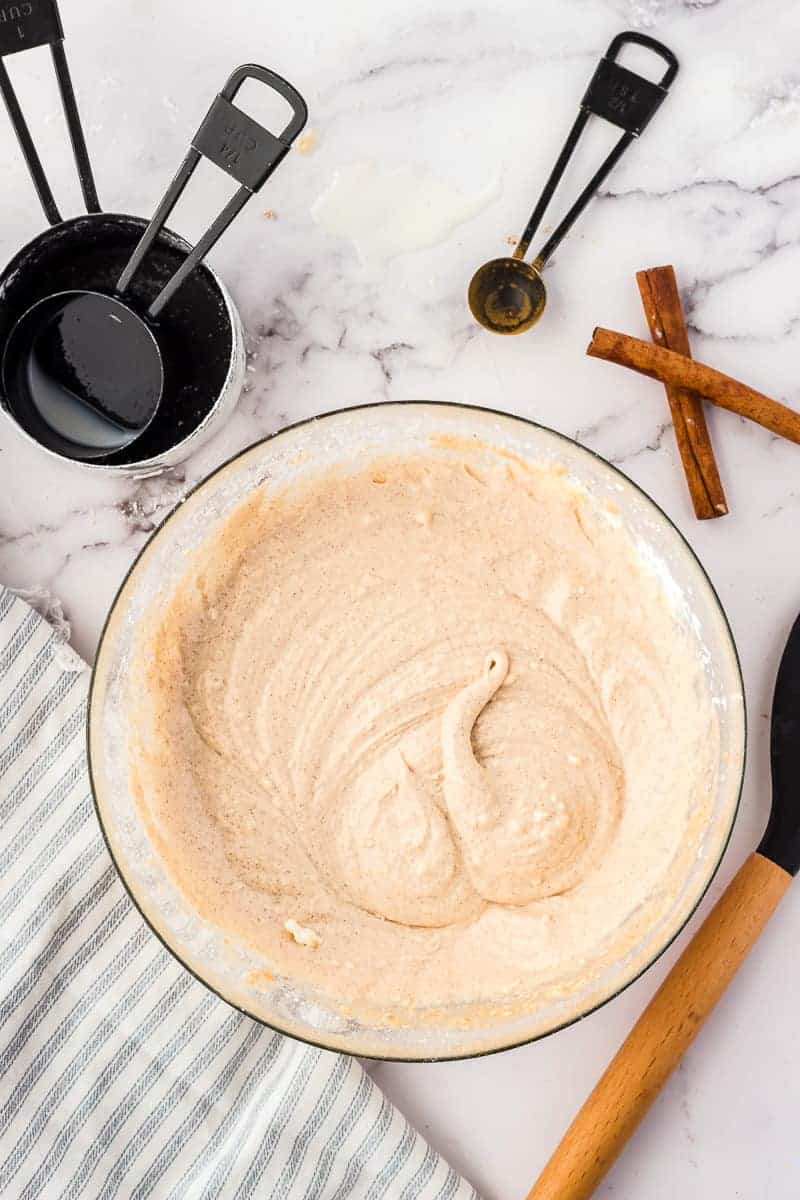 Glass mixing bowl with cinnamon cream cheese frosting after mixing