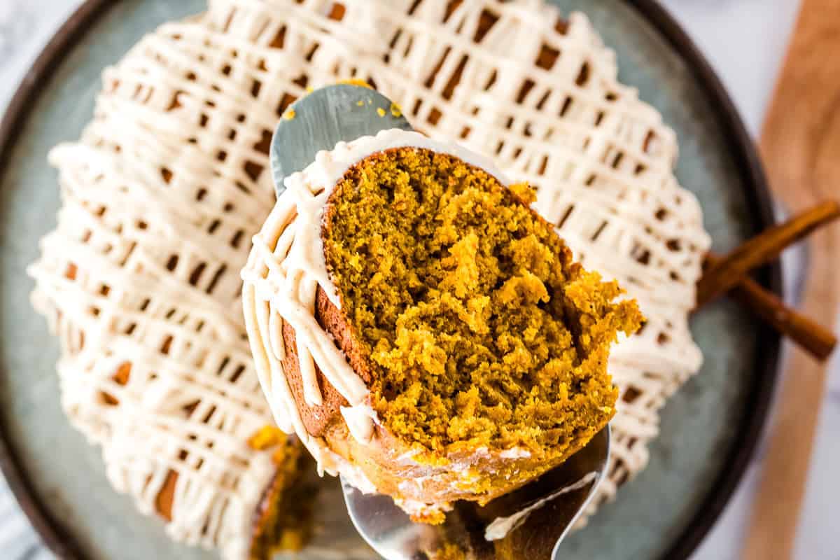 Slice of pumpkin bundt cake with cinnamon cream cheese frosting on cake server