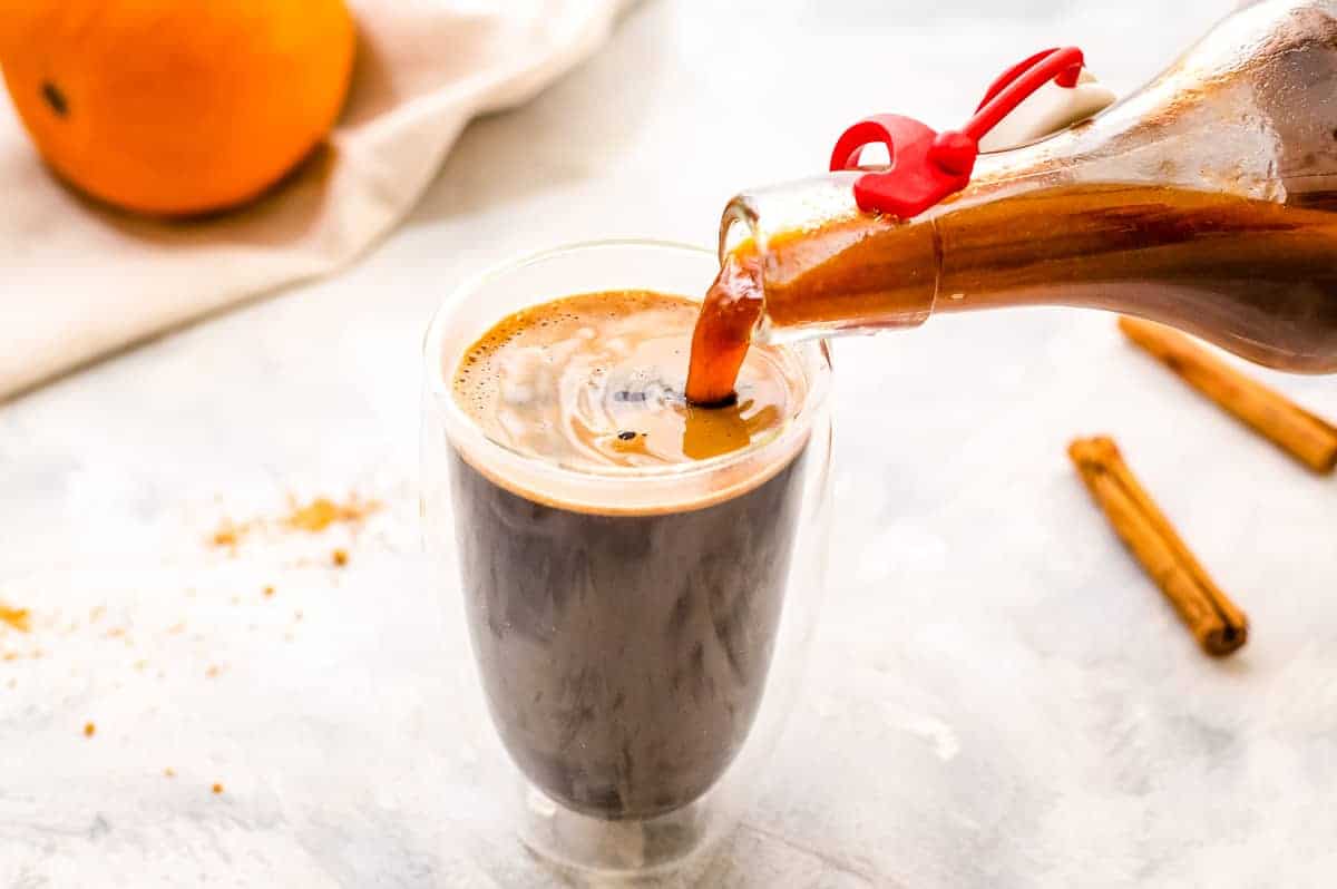 Bottle pouring pumpkin syrup into coffee