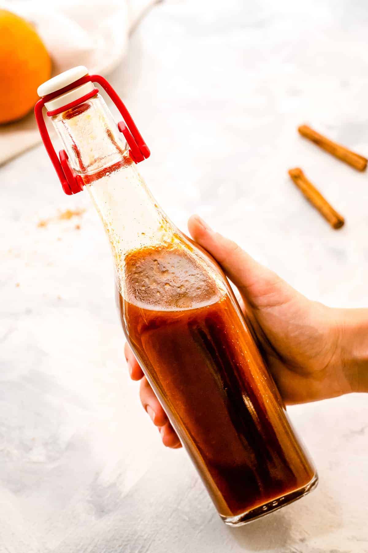 Hand holding glass bottle with pumpkin pie syrup in it