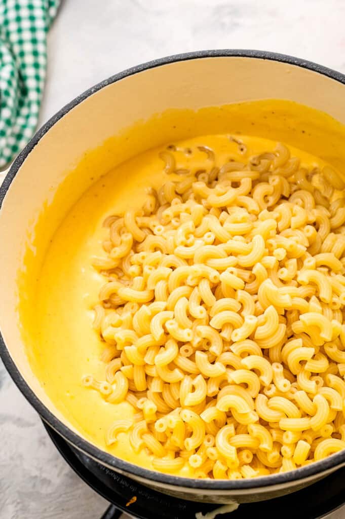 Dutch oven with cheese sauce and cooked elbow macaroni