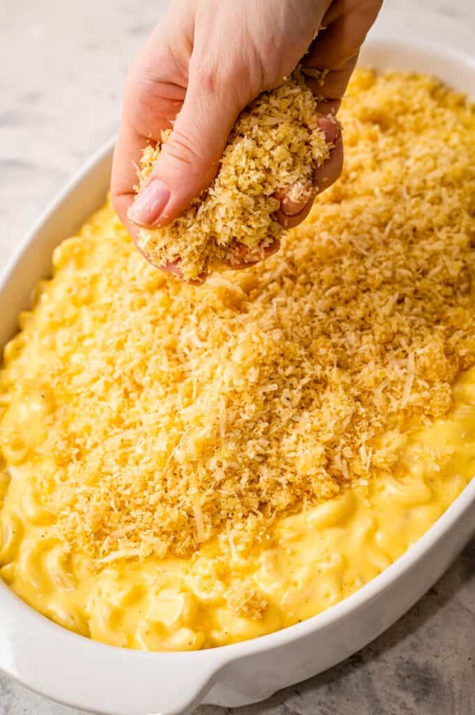 Hand sprinkle buttery breadcrumb topping on mac and cheese