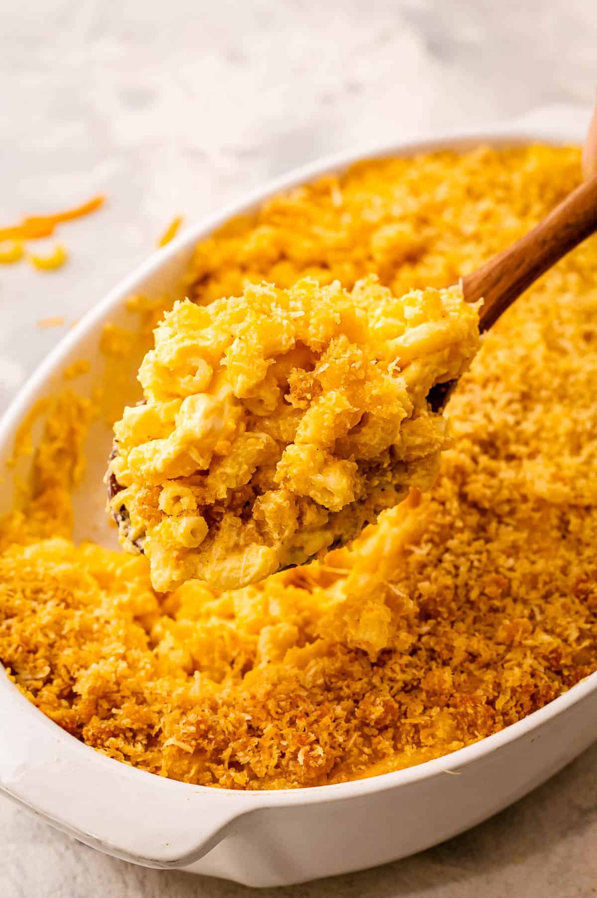 Spoon scooping mac and cheese out of casserole dish