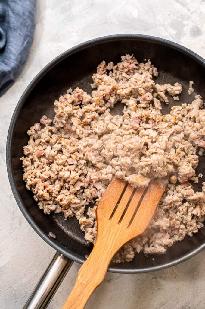 Spatula stirring sausage in skillet