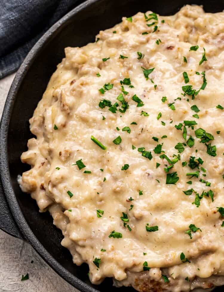 Black skillet with sausage gravy topped with chopped parsley